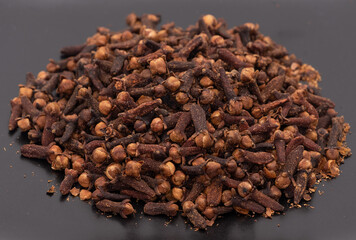 A pile of cloves close up isolated on a black plate