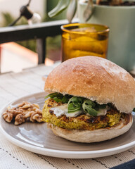 Chickpeas veggie burger on a table with a tonic water glass.
