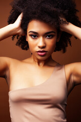 pretty young african american woman with curly hair posing cheerful gesturing on brown background, lifestyle people concept