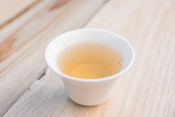 Beautiful porcelain tea cup close up shot. Hydrating pale liquor in it.
Fresh natural yellow tea.
