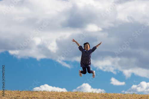 秋の公園の芝生でジャンプして遊んでいる可愛い子供 Wall Mural Zheng Qiang