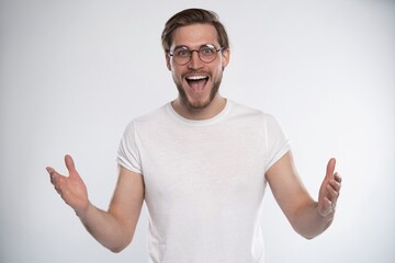 Attractive young bearded man looks with astonishment into camera, being amazed with news. Facial...