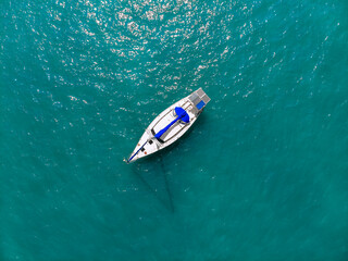 Aerial wonderful view of a enormous white and blue yacht sailing across the blue lagoona