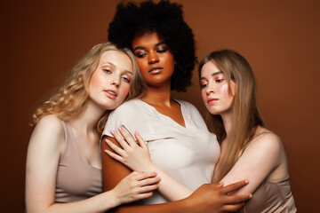Obraz premium young pretty caucasian, afro, scandinavian woman posing cheerful together on brown background, lifestyle diverse nationality people concept