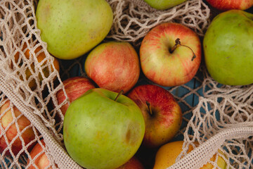 Top view of organic apples in eco friendly meshed shopping bag on a blue rustic board. No waste, zero plastic, eco friendly, reusable concept