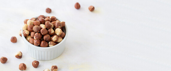 Hazelnuts in plate on white background - copy space