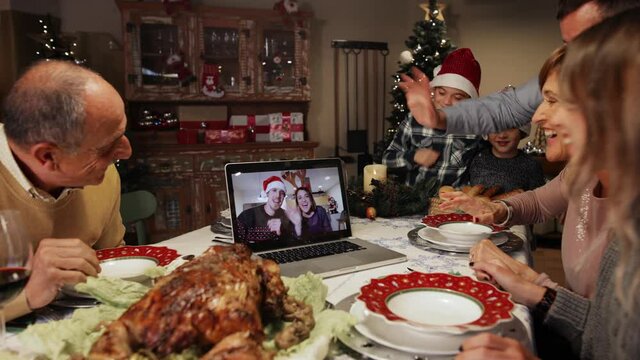 A couple on a screen and some relatives celebrating Christmas using a video call. People greeting their family and friends on Christmas eve online. Social distancing, self isolation quarantine.