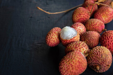 Fresh lychee fruit on a black wooden background