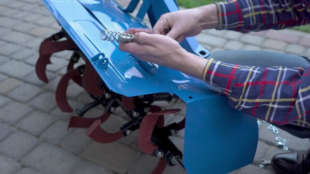 assembly of equipment for a tractor,man assembles a cultivator for a motoblock