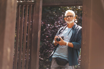 Gray-haired senior man with a camera. Retired freelance photographer. Free photo journalism.