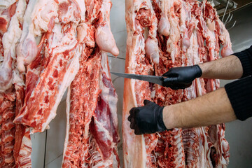 Close up butcher hand cutting hanging sheep meat in the butcher shop.  Cattles cut and hanged on...