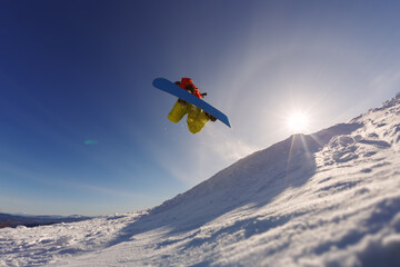 Naklejka na ściany i meble Snowboarder jumping against the sunset sky