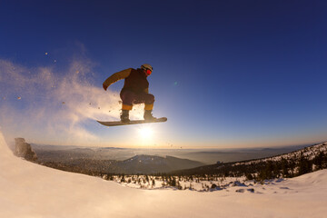 Snowboarder jumping against the sunset sky
