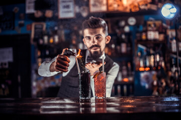 Charming barman is pouring a drink at the bar counter