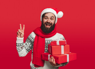 Happy man with Christmas presents showing peace sign