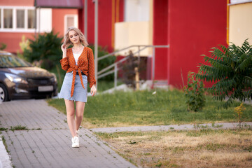 A young woman walks along the sidewalk along the houses.