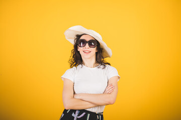 beautiful girl in a white t-shirt and a big white hat on a yellow background in the studio