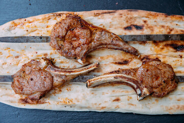 Grilled or barbecued lamb chop meat steaks on the black background.