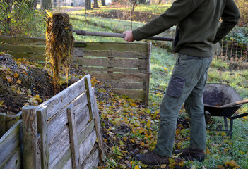 shuffling compost for aeration and better rot. the gardener uses a shovel and pitchfork in his...