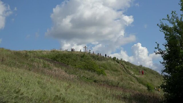 People are climbing to the Orthodox Cross at the top of Alexandrov mountain. Pereslavl-Zalessky, Russia.