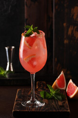 Alcoholic cocktail. Drink with grapefruit, elderberry, ice and mint in a glass on a wooden board. Bar menu. Background image, copy space, vertical