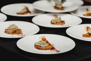 several white plates on a black table with baked sweet pumpkin and guacamole. Mexican cuisine at the restaurant