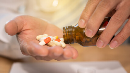 Pills and bottles in hand Concept of medicine and health care In the living room Healthy lifestyles, medications, supplements, and people's concepts.