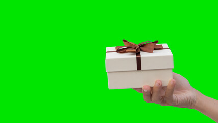 Young man holding a white cardboard box with a bow on green background as a gift on New Year's Day.