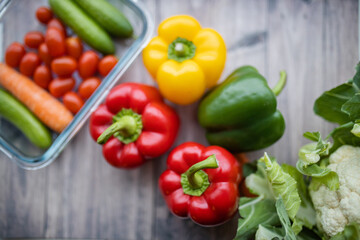 Fresh and colorful bell peppers and other vegetables on wooden table