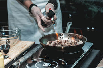 The chef cooks the small octopus on a metal frying pan