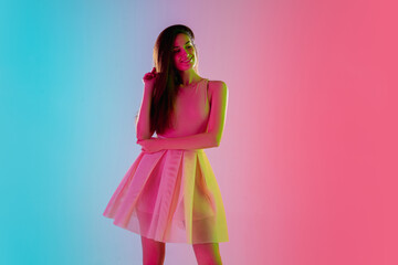 Confidence. Beautiful seductive girl in fashionable, romantic outfit on gradient pink-blue background in neon light. Half-length portrait. Copyspace for ad. Summer, fashion, beauty, emotions concept.