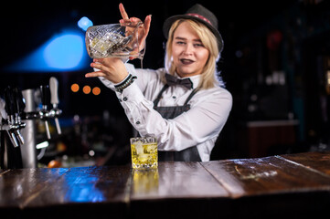 Girl barman concocts a cocktail behind the bar