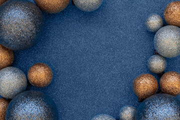Blue and golden Christmas baubles decoration on blue glittering background. Top view. Copy space. New Year or Christmas