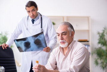 Young male doctor and old patient in antismoking concept