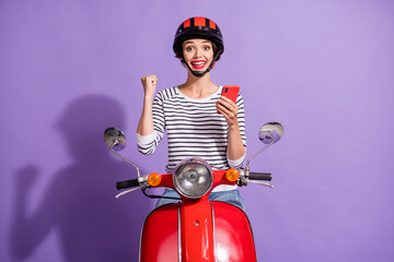 Photo of lady ride moped raise fist hold smartphone wear helmet striped shirt isolated violet color...