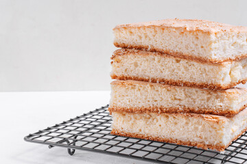 Sponge cake cut into square pieces in stack on the metallic lattice. Base for a cake
