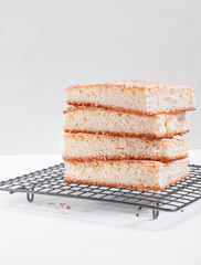 Sponge cake cut into square pieces in stack on the metallic lattice. Base for a cake