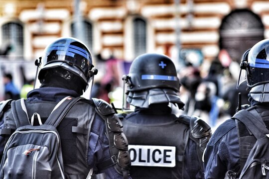 Rear View Of Police In Uniforms Standing Outdoors