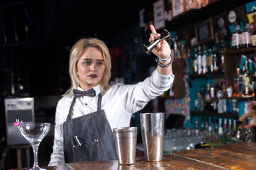Girl barman makes a cocktail in the alehouse