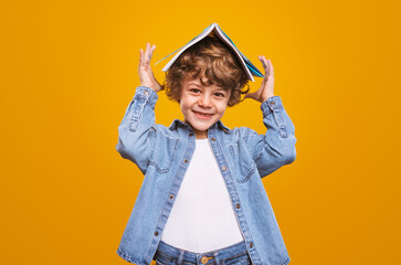 Cheerful schoolboy with copybook on head