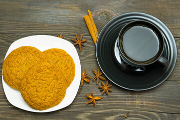 A cup of coffee, cinnamon, star anise, cloves and cookies on the table. Composition with coffee.