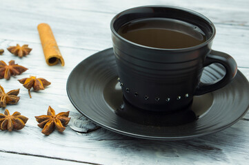 A cup of coffee, cinnamon, star anise, cloves on the table. Aromatic coffee with spices. Composition with coffee.
