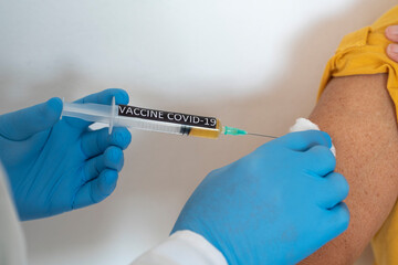 Coronavirus. The hands of a doctor injecting the covid-19 coronavirus vaccine to a woman in a...