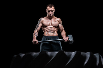 Professional sportsman stands with a sledgehammer in front of a rubber wheel. Functional training concept. © andy_gin