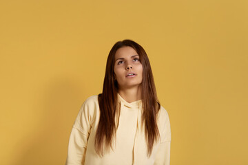 Displeased sleepy overworked caucasian woman in yellow hoodie looking up from weariness, feels fatigue after hard work. Isolated on a yellow background.