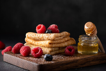 thin homemade pancakes with berries and honey