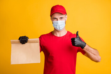 Photo of promoter man hold package raise thumb up wear mask red t-shirt hat isolated yellow color background