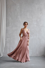 Fototapeta premium Beautiful sexy woman in a light beige silk dress. Noise, out of focus