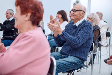 a group of senior citizens applaud in the conference room