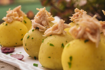 Bolas de papa rellenas con pollo deshilachado encima y trozos de perejil adornado con aceitunas
